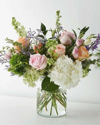 With its beautiful blend of roses, larkspurs, hypericum berries, Queen Anne's Lace, trick dianthus, and Limonium, this artful arrangement could have inspired a Monet masterpiece.