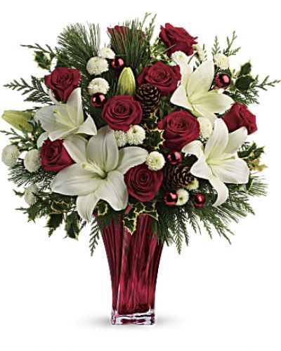 <p>Send them the wonders of winter with beautiful red roses, snow white lilies and fresh winter greens arranged in an elegant glass vase.</p>
<p>Red roses, white asiatic lilies and white button chrysanthemums are accented with fresh flat cedar, variegated holly, white pine, pinecones and red ornament balls.</p>