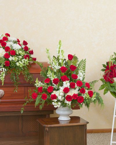 <p>Red and white casket spray, urn and wreath.</p>
